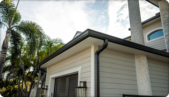 Contemporary house with black gutter system and downspout installed along light gray siding