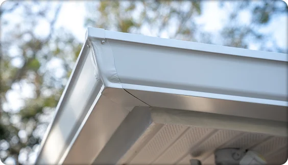 Modern home exterior with black aluminum gutters, soffit lighting, and palm tree against blue sky