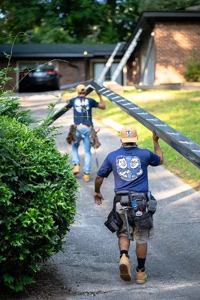 2 people carrying ladders in the brothers that just do gutters uniforms